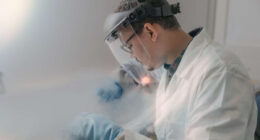 Engineer in white lab coat working with cryogenics 